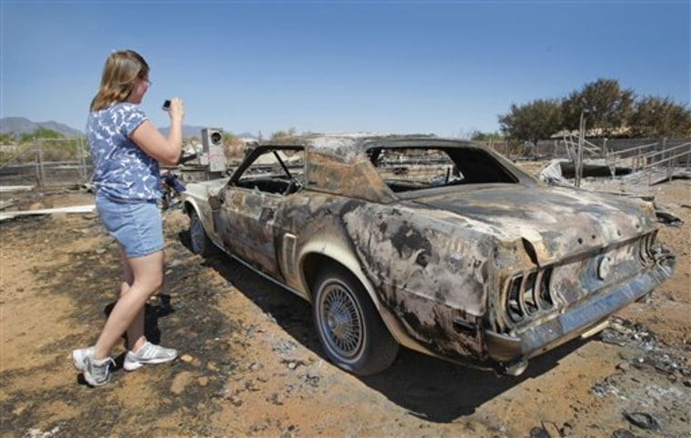 Stephanie Jaco looks over  her  Mustang  that was destroyed along with her  home from the Monument Fire near Sierra Vista,  Ariz. on Wednesday, June 22, 2011.   The first of three major wildfires that have been burning in Arizona for weeks is expected to be fully contained by Wednesday evening, and fire crews are making major strides in corralling the other two.  (AP Photo/The Arizona Republic, David Kadlubowski)